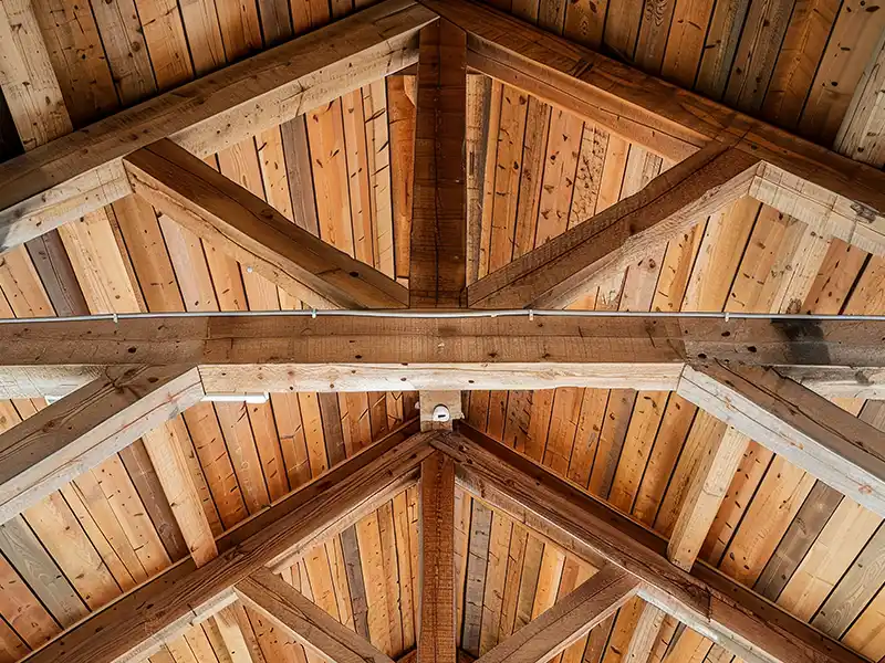 Traitement de charpente dans le Gard - Rénovation Sud Vue rapprochée d'un plafond en bois avec des poutres et des planches entrecroisées, disposées selon un motif géométrique, mettant en valeur les textures et le grain du bois naturel - idéal pour souligner les avantages du traitement de charpente.